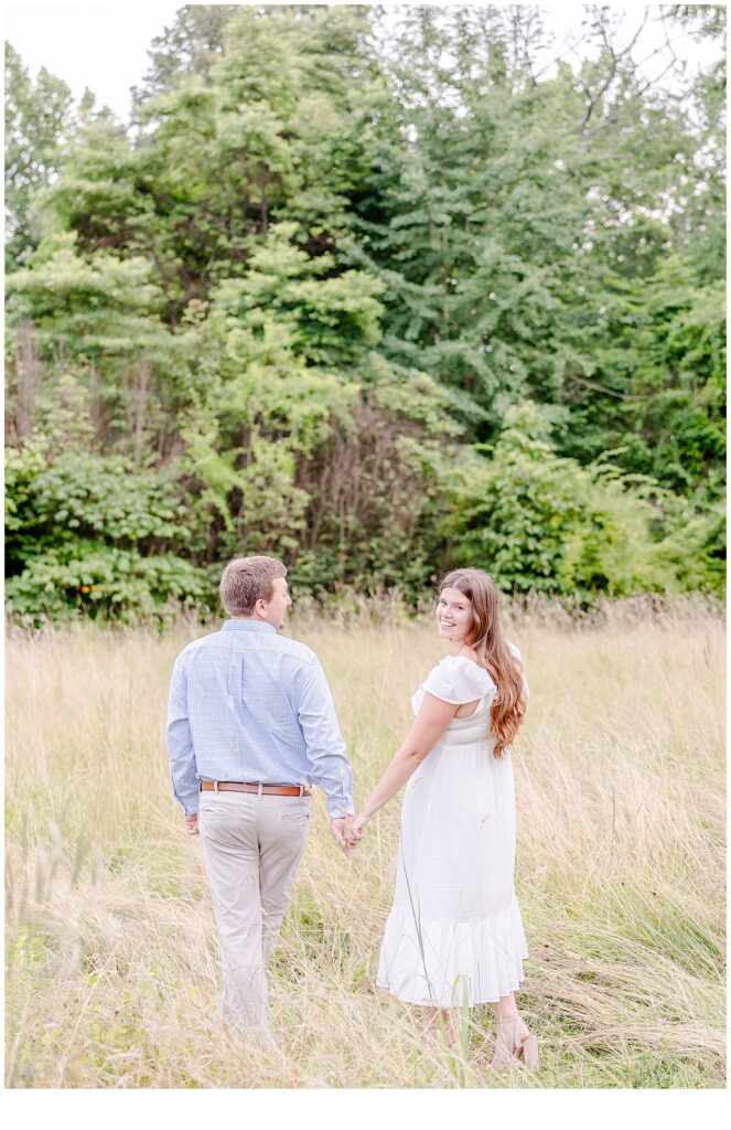 engaged couple walking through meadows 