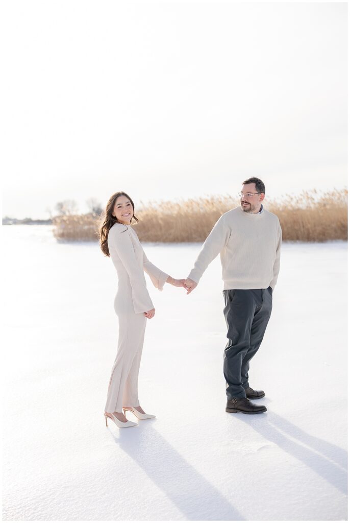 Couple walking on frozen beach during Manasquan NJ engagement session